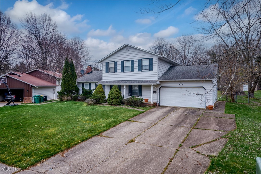 White two-story house with dark shutters, attached garage, and wide concrete driveway.