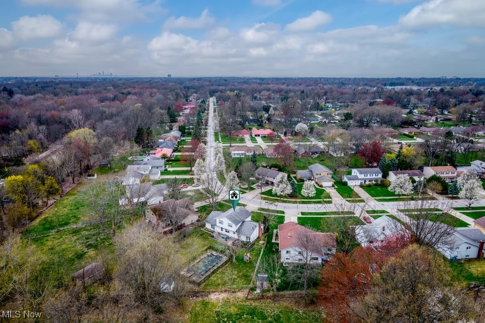 Aerial view of a residential neighborhood with a straight road and a marked house near the center.