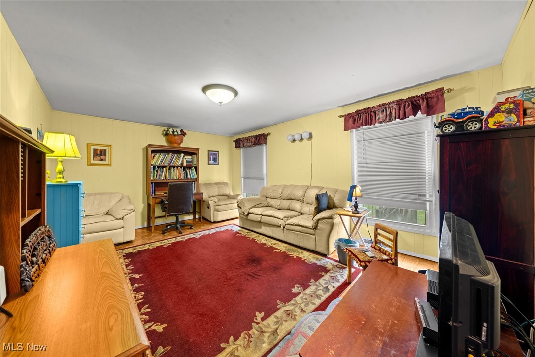 Living room with beige sofas, yellow walls, and a large red patterned rug.