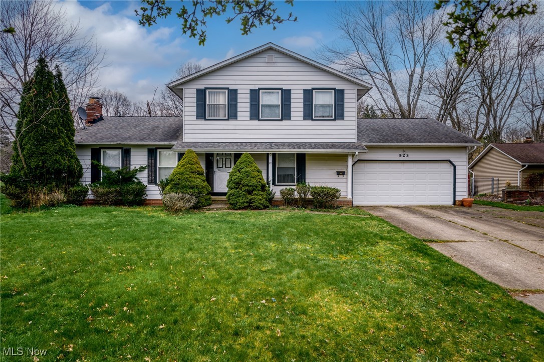 White two-story house with dark shutters, a two-car garage, and a green front lawn.