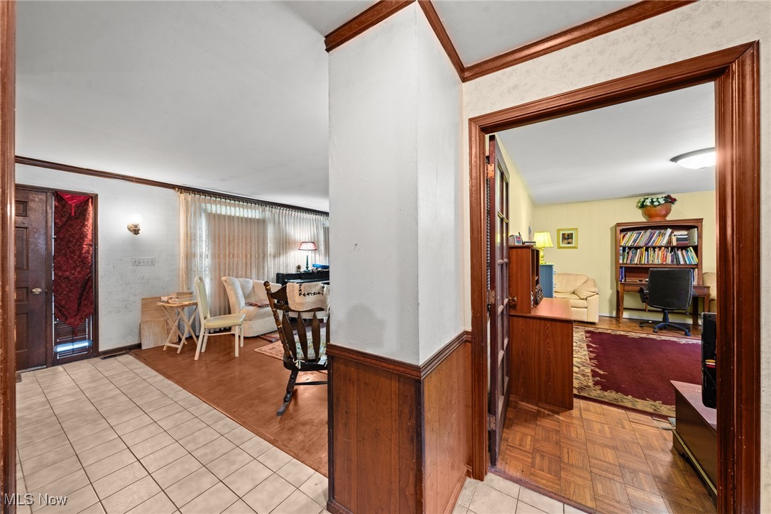 Tiled entry and dining area beside a wood-trimmed doorway to a furnished home office.