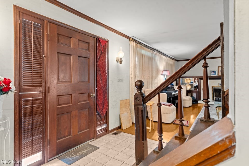 Entry foyer with a dark wood front door, tiled floor, and staircase beside living room.