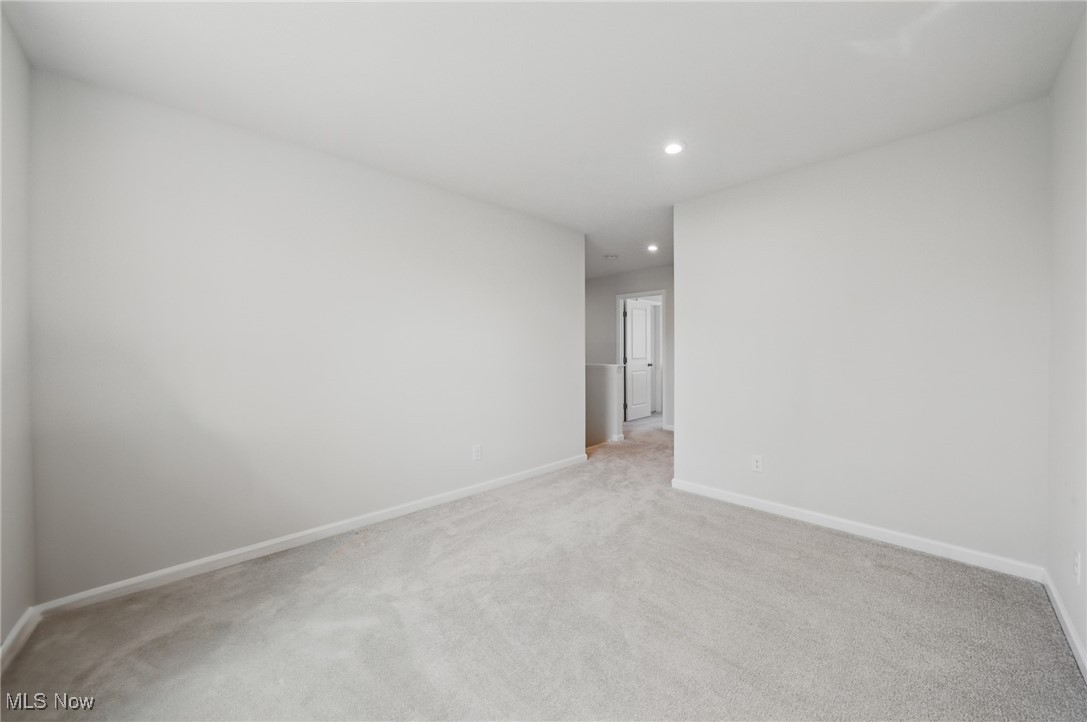 Empty carpeted room with recessed lights and an open doorway to the hallway.