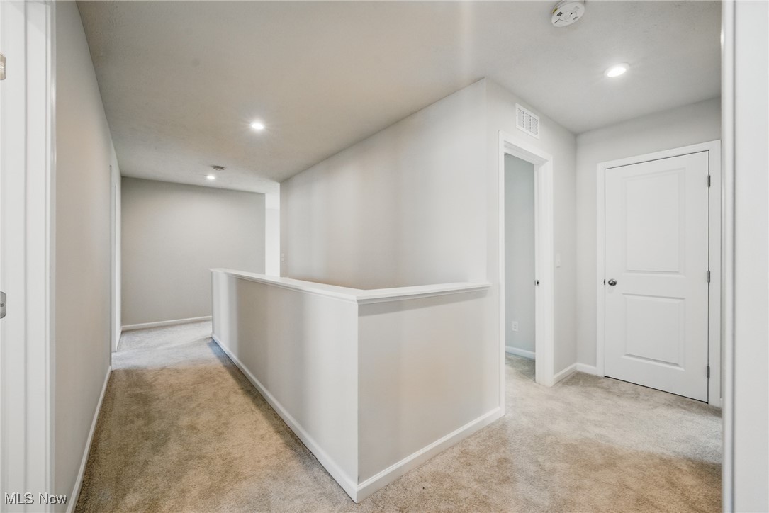 Carpeted upstairs landing with a half-height railing and two closed doors.