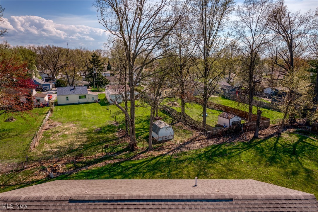 Aerial view of a fenced backyard with mature trees and two sheds.