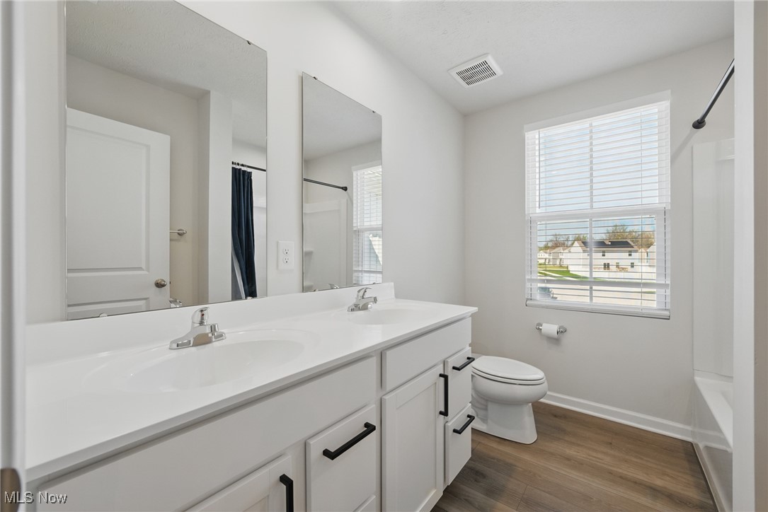 Bathroom with a long double-sink vanity, large mirrors, and a window with white blinds.