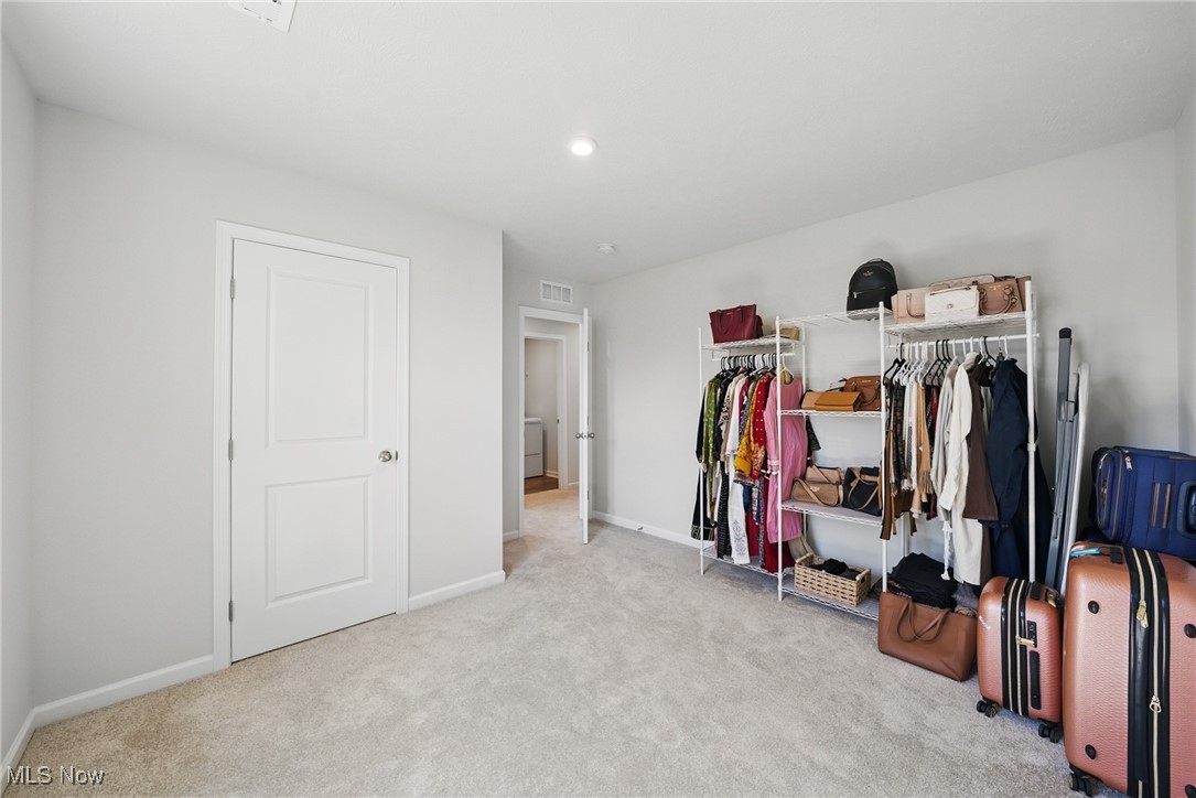 Walk-in dressing room with open clothing racks, handbags, and suitcases.