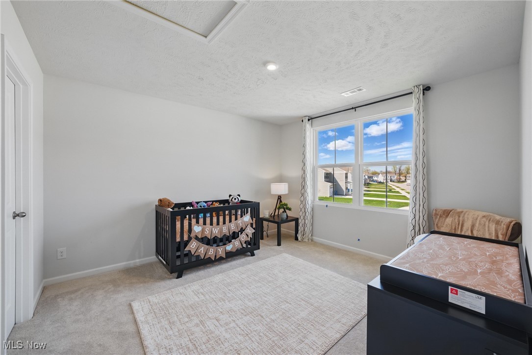 Nursery with a black crib, baby banner, changing table, and large window overlooking the neighborhood.
