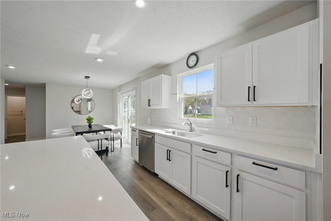 Bright white kitchen with a long peninsula, hexagonal tile backsplash, and adjoining dining area.