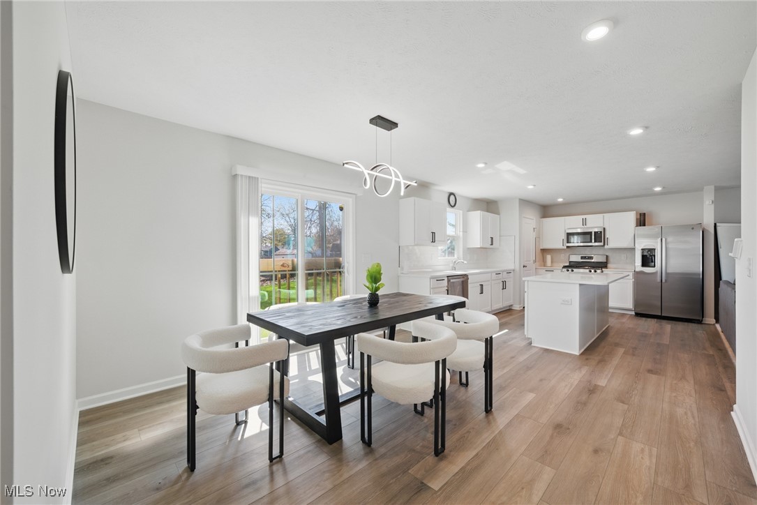Open-plan kitchen and dining area with a white island, stainless steel appliances, and sliding doors to the yard.