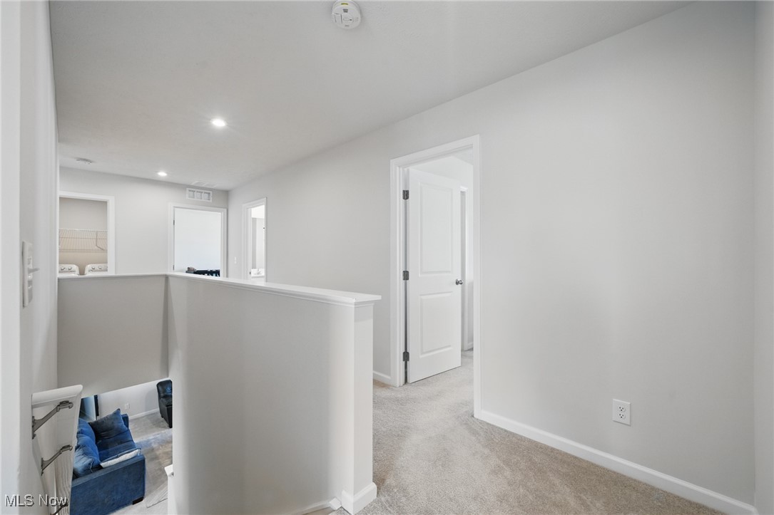 Carpeted upstairs landing overlooking a lower level with a blue sofa, with laundry appliances visible nearby.