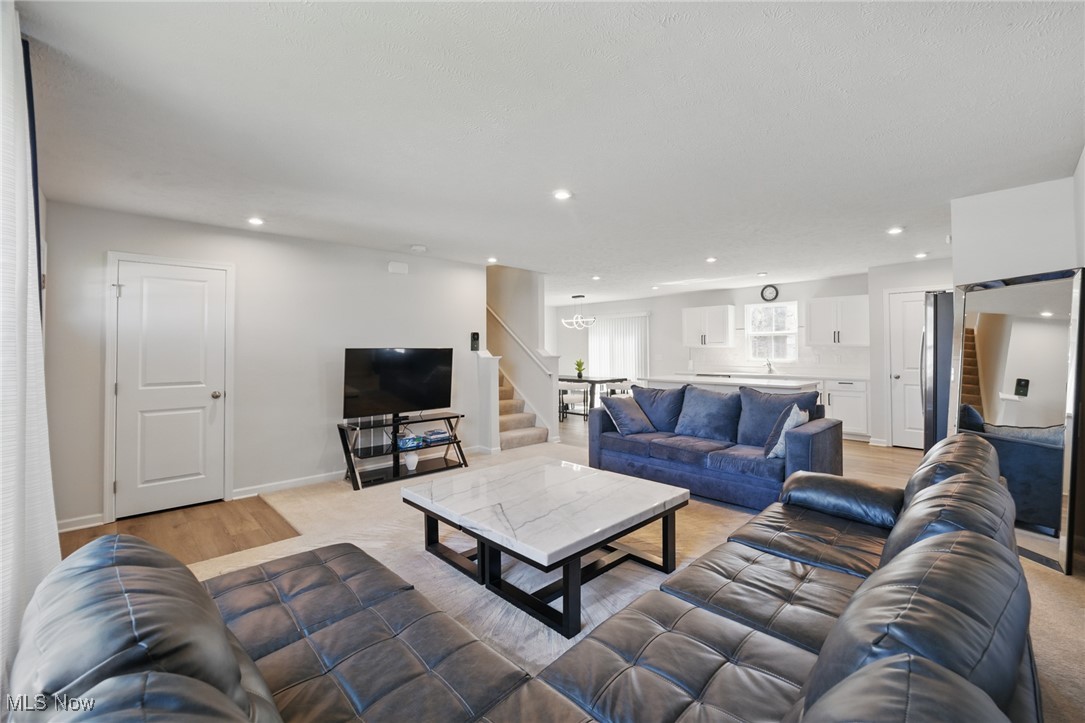 Open-plan living room with blue sofas and a white kitchen beyond.