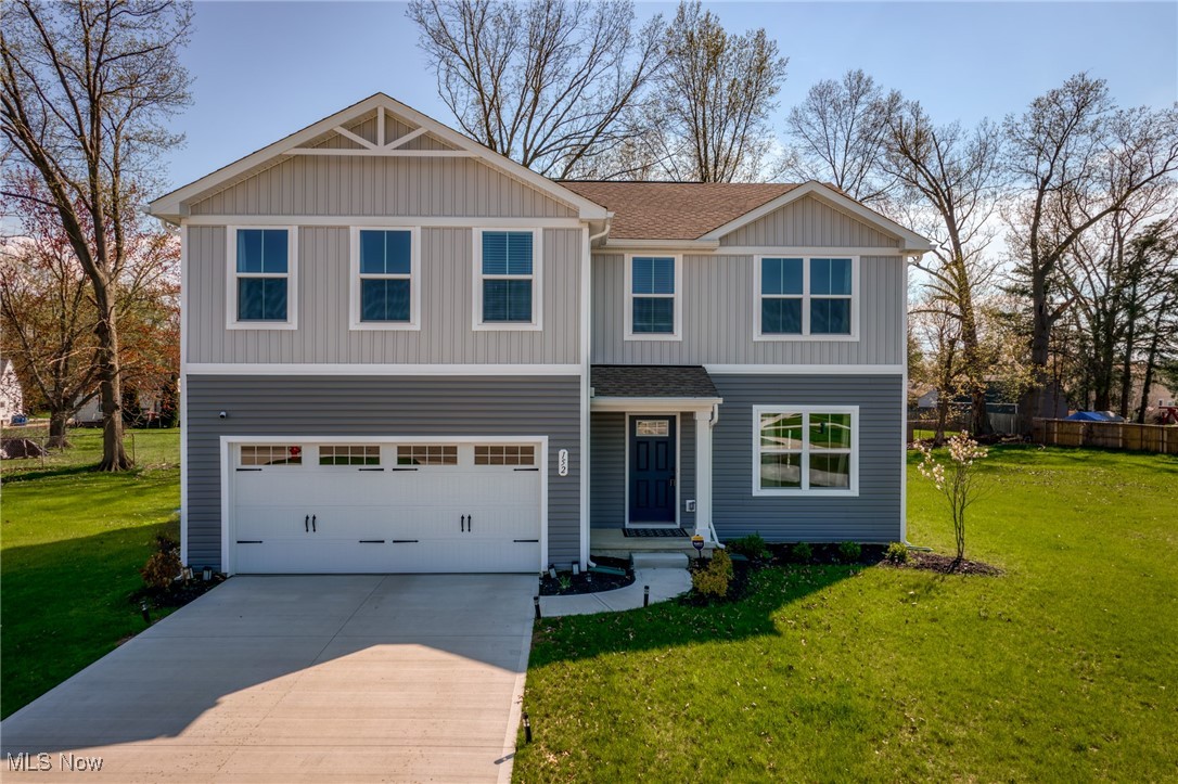Two-story gray-and-white house with a double garage, blue front door, and wide concrete driveway.