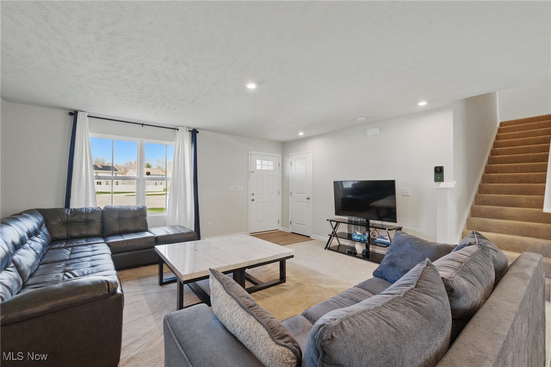 Living room with two sectional sofas, a marble-look coffee table, and a carpeted staircase.