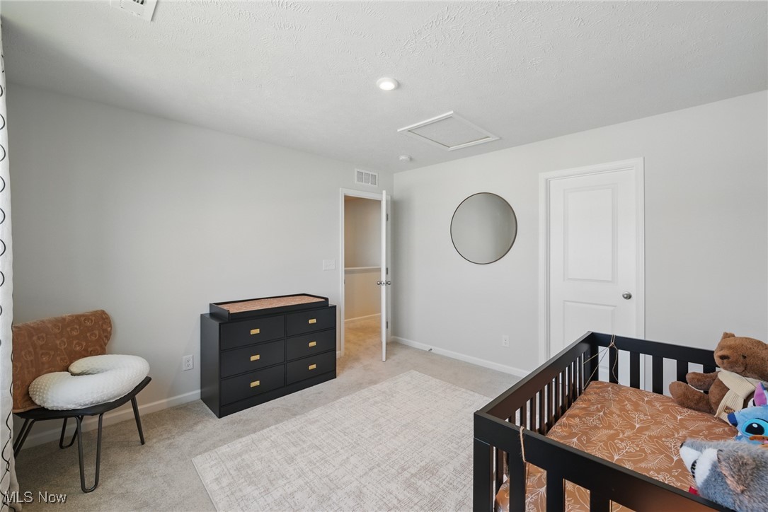Nursery with a black crib, stuffed toys, dresser, and round wall mirror.