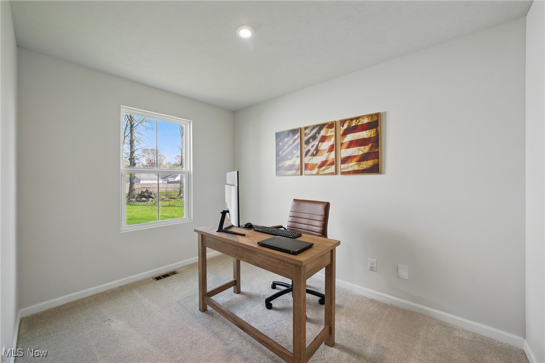 Home office with a wooden desk, brown chair, and three-panel American flag artwork.