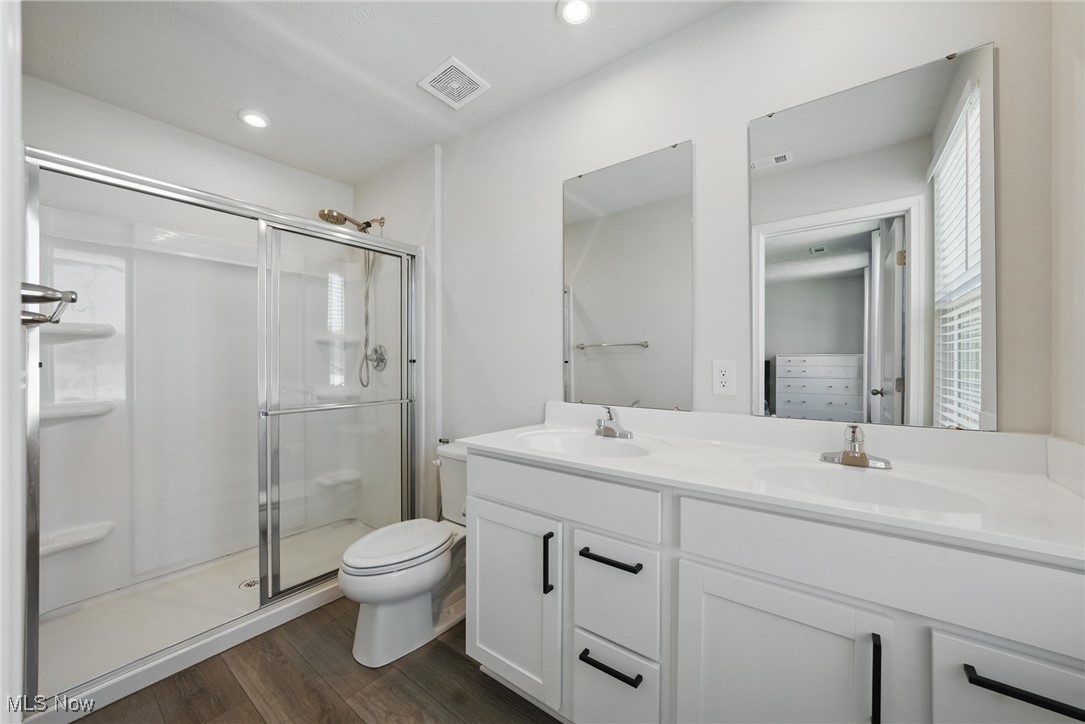 Bathroom with a glass-enclosed shower and white double-sink vanity.