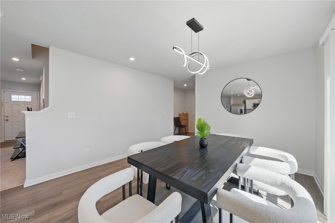 Dining room with a dark wood table, white upholstered chairs, and a modern pendant light.