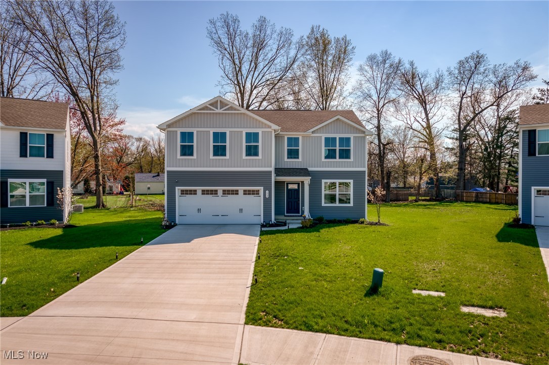 Two-story gray-and-white house with an attached garage, broad driveway, and green lawn.