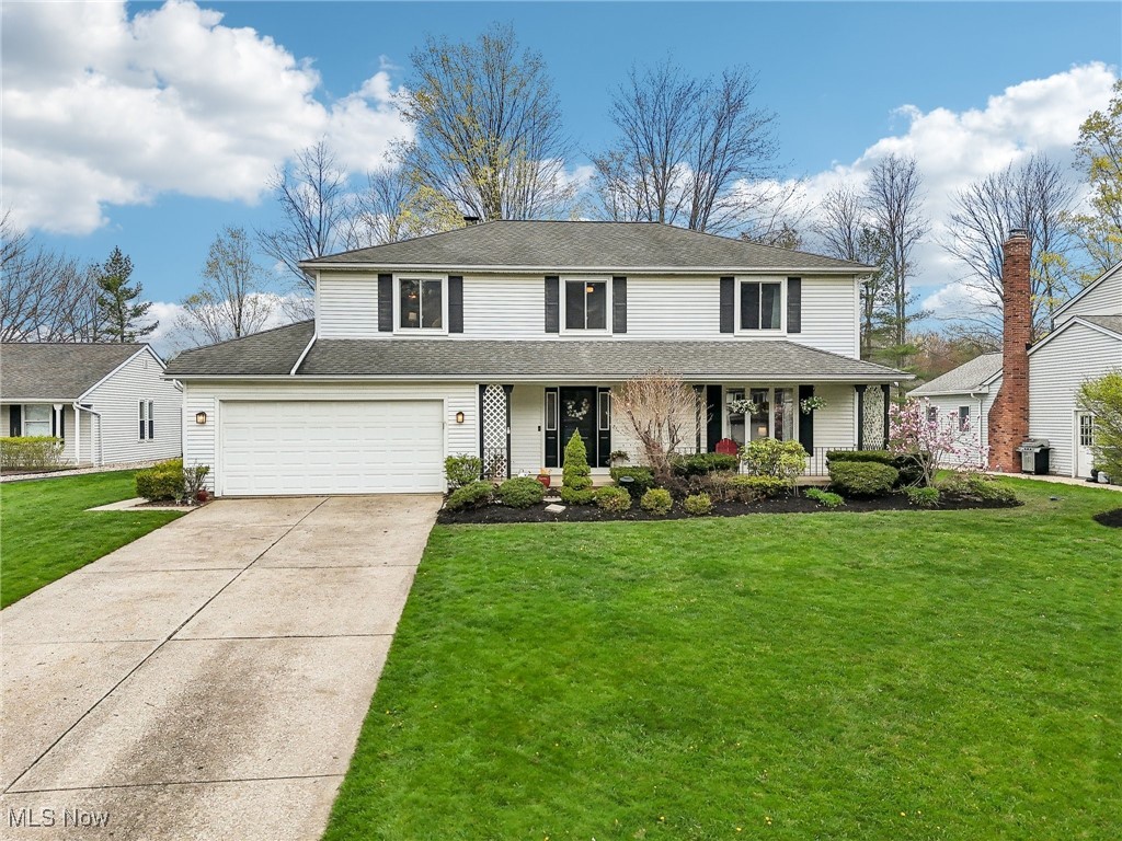 Two-story white-sided home with attached garage, covered porch, and landscaped front lawn.