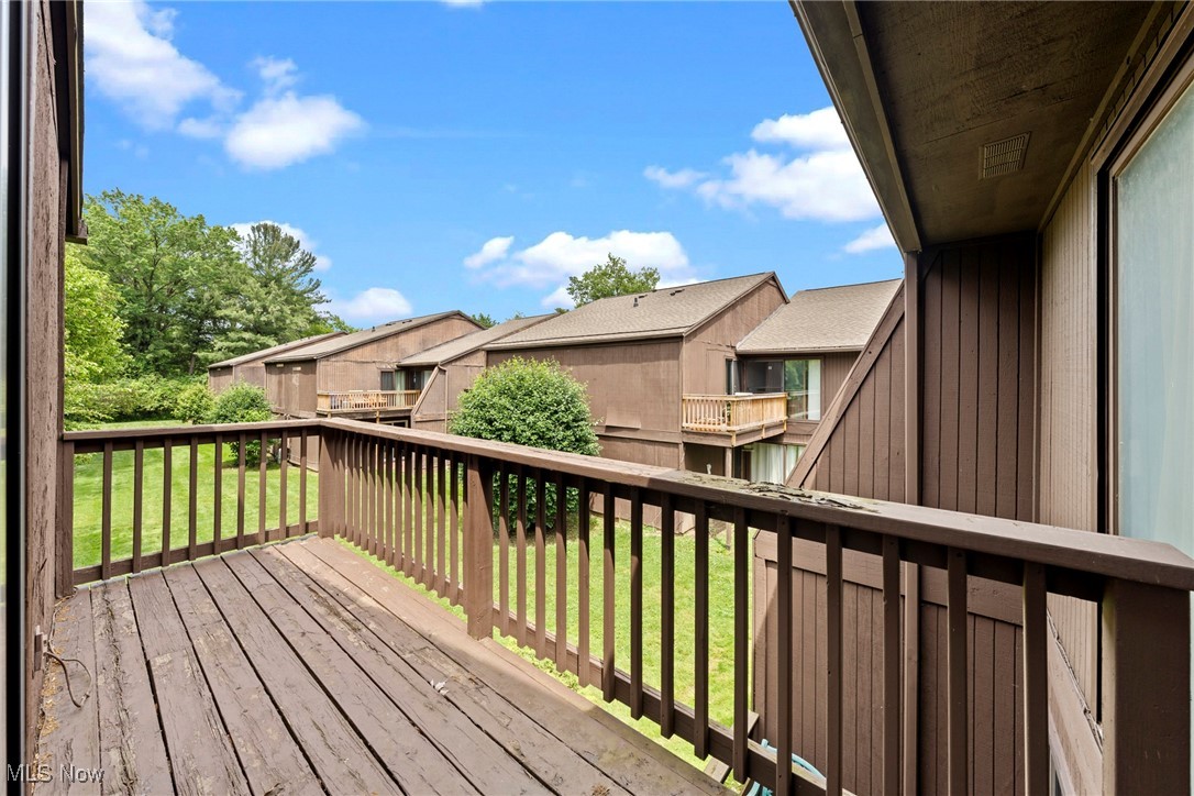Wooden balcony overlooking a grassy courtyard and neighboring townhomes.