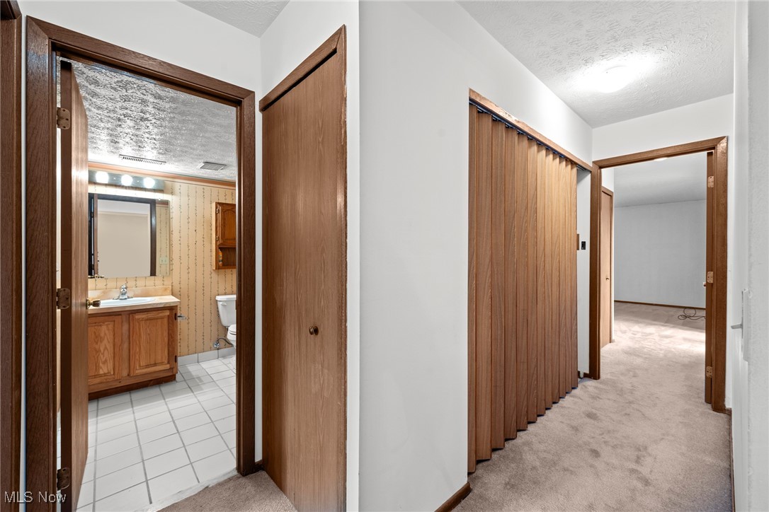 Carpeted hallway with a folding wood closet door and an open bathroom doorway.