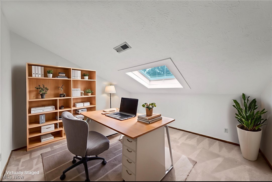 Home office with a skylight, wooden shelving, and a desk with a laptop.