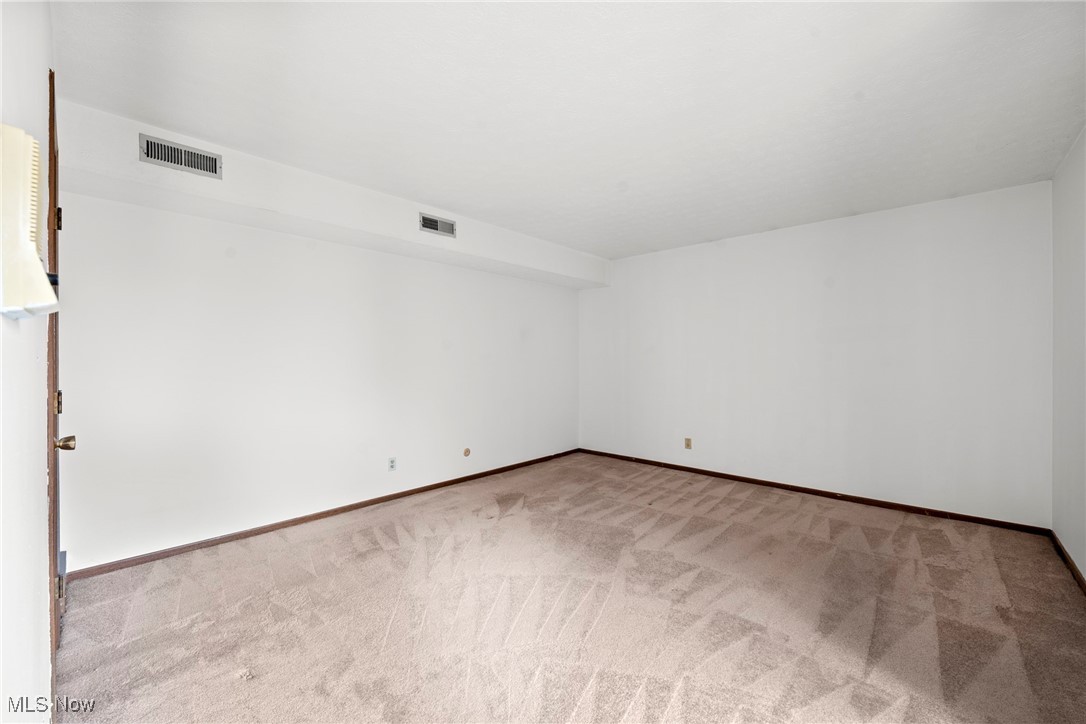 Vacant carpeted room with white walls and a partially open door.