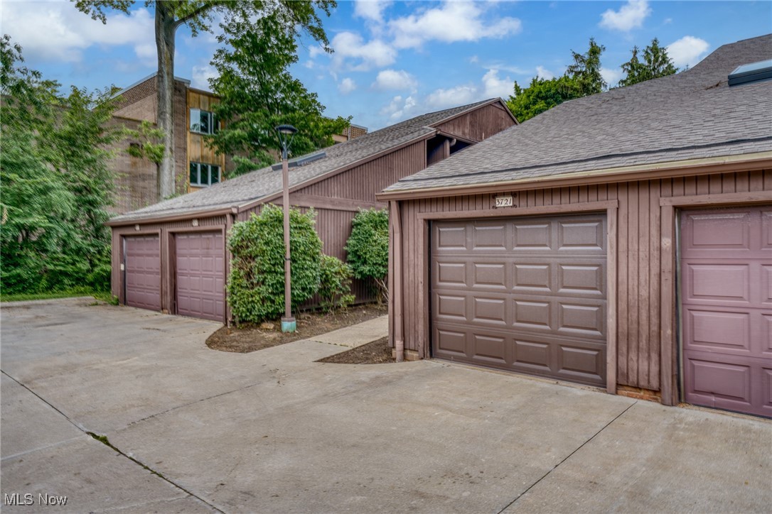 Brown-sided garage bays with multiple doors and a broad concrete driveway.