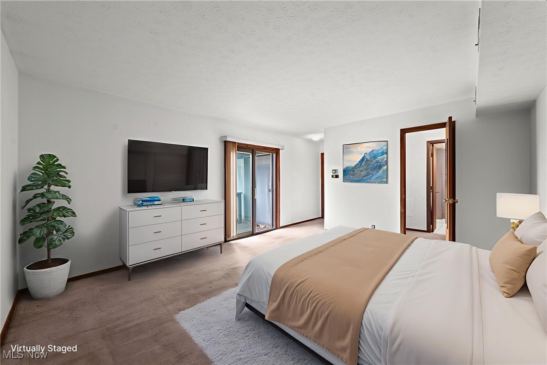 Bedroom with white and tan bedding, a wall-mounted television, and sliding glass doors.