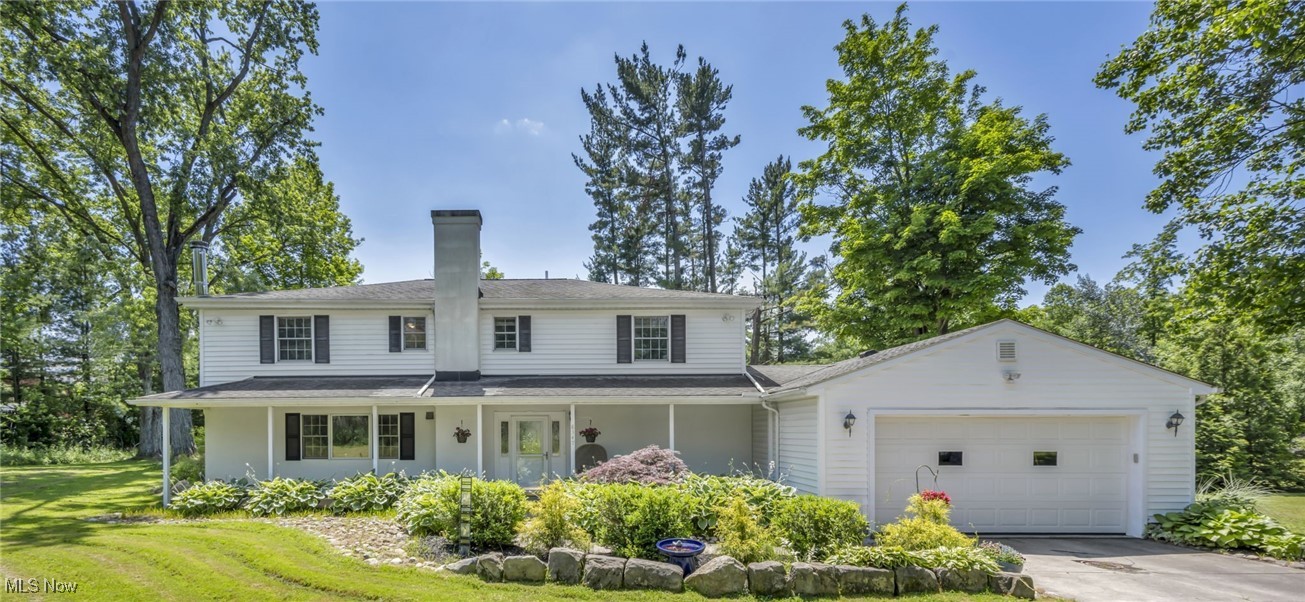 White two-story house with a covered porch, attached garage, and landscaped front garden.