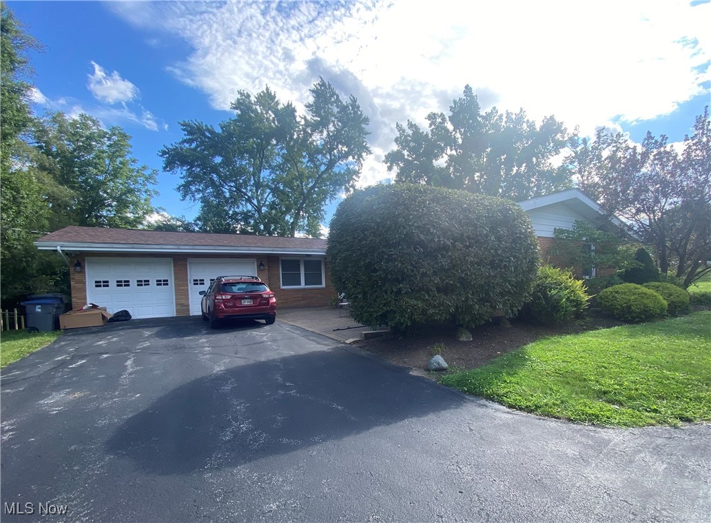 Brick ranch home with a two-car garage, red car in the driveway, and mature landscaping.