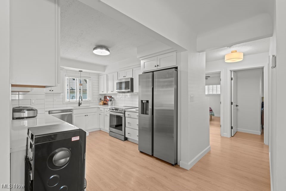 White kitchen with stainless steel appliances, subway tile backsplash, and washer and dryer.