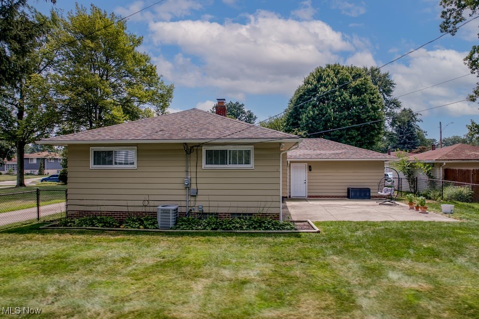 Rear of a beige single-story home with an attached garage and grassy backyard.