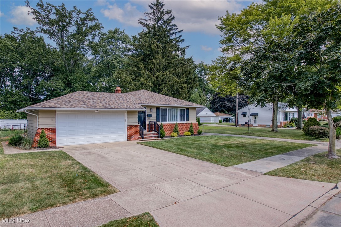 Ranch-style home with a two-car garage, brick lower facade, and broad driveway.
