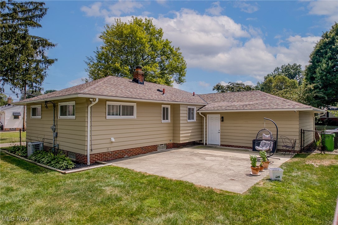 Rear exterior of a tan ranch home with a concrete patio and lawn.