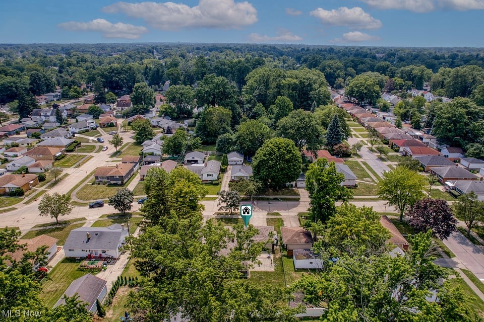 Aerial view of a leafy neighborhood with detached homes and a marker identifying the property.