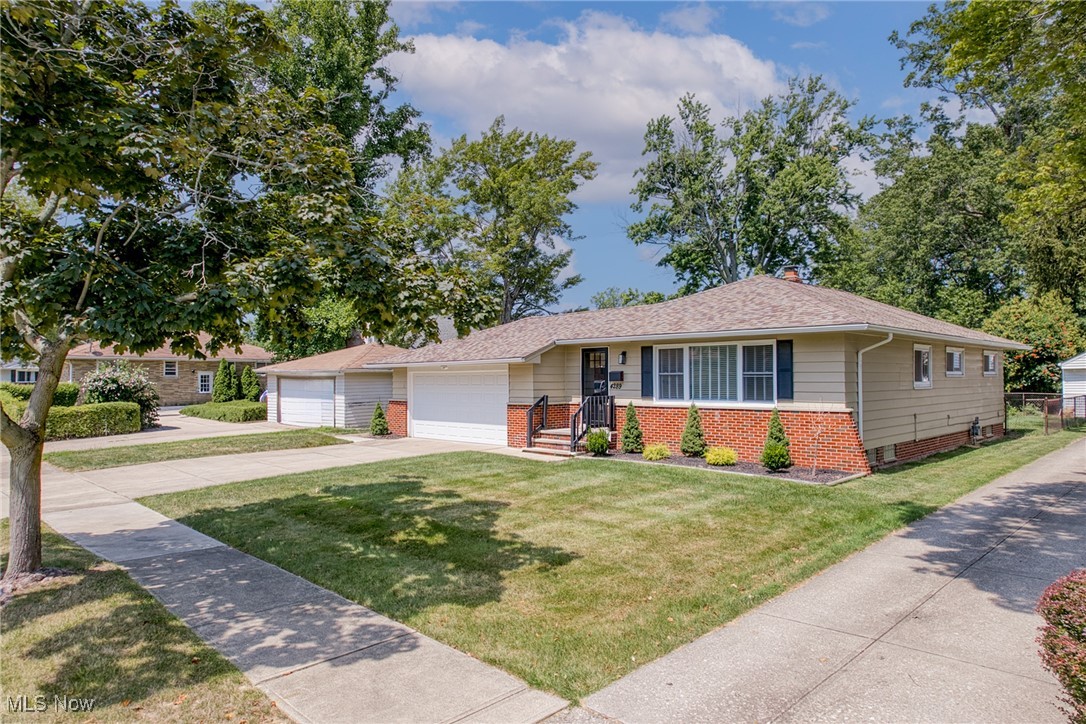 Single-story ranch home with a brick lower facade, attached garage, and tree-shaded lawn.