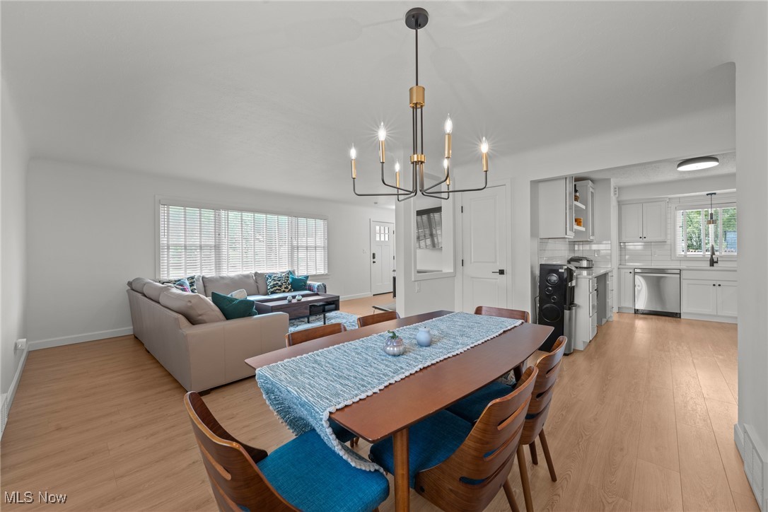 Open-plan dining and living room with a blue-accented dining table, beige sectional, and adjoining white kitchen.