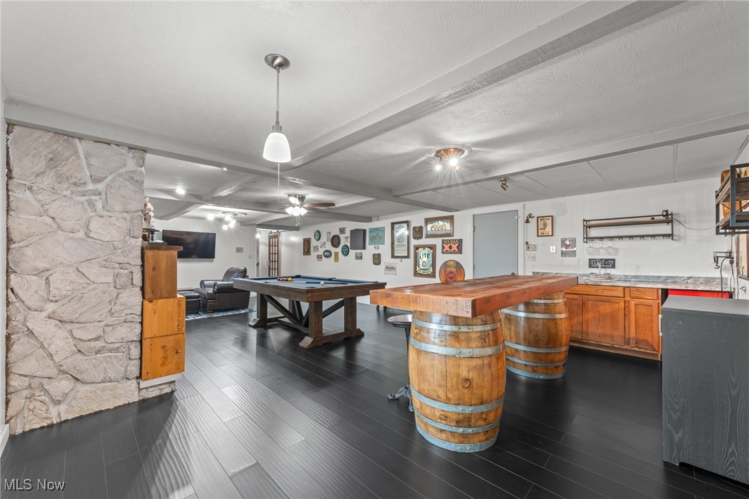 Basement recreation room with a pool table and a barrel-based bar beside a stone accent wall.