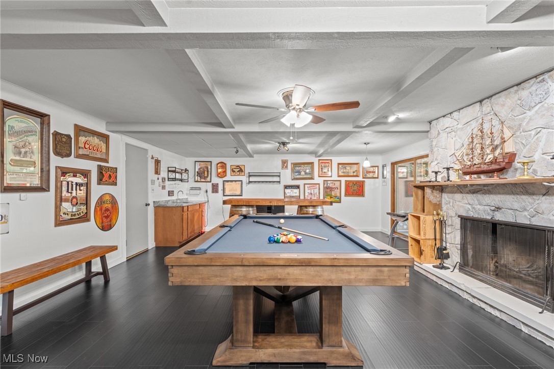 Basement game room with a blue-felt pool table and stone fireplace.