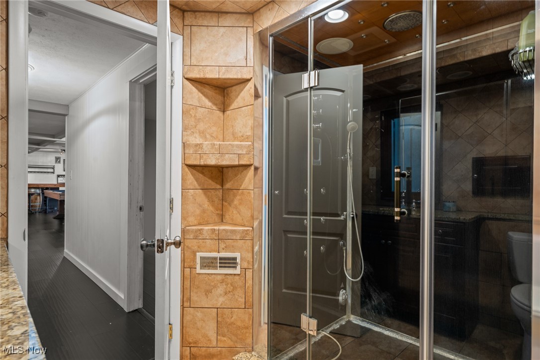 Bathroom with a glass-enclosed shower, dark tile, and built-in wall niches.
