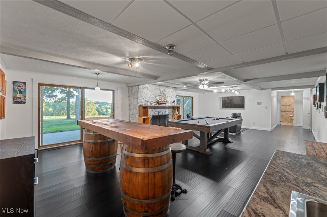 Recreation room with a pool table, barrel-base table, stone fireplace, and sliding doors to the lawn.
