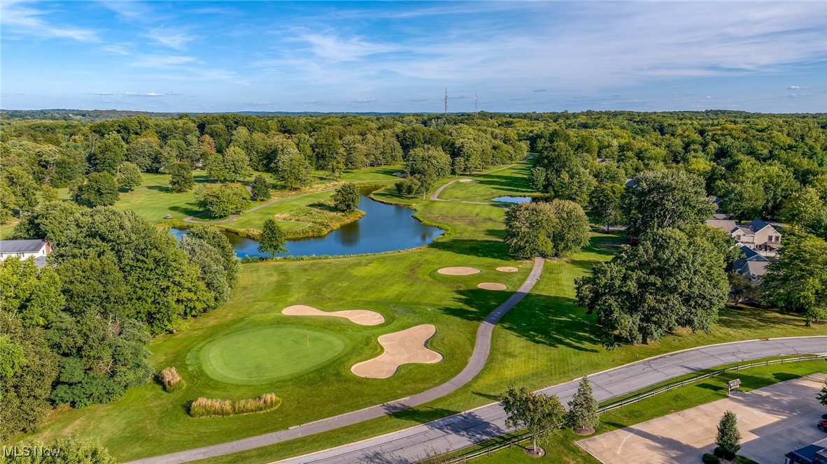 Aerial view of a golf course with greens, sand bunkers, and a pond.