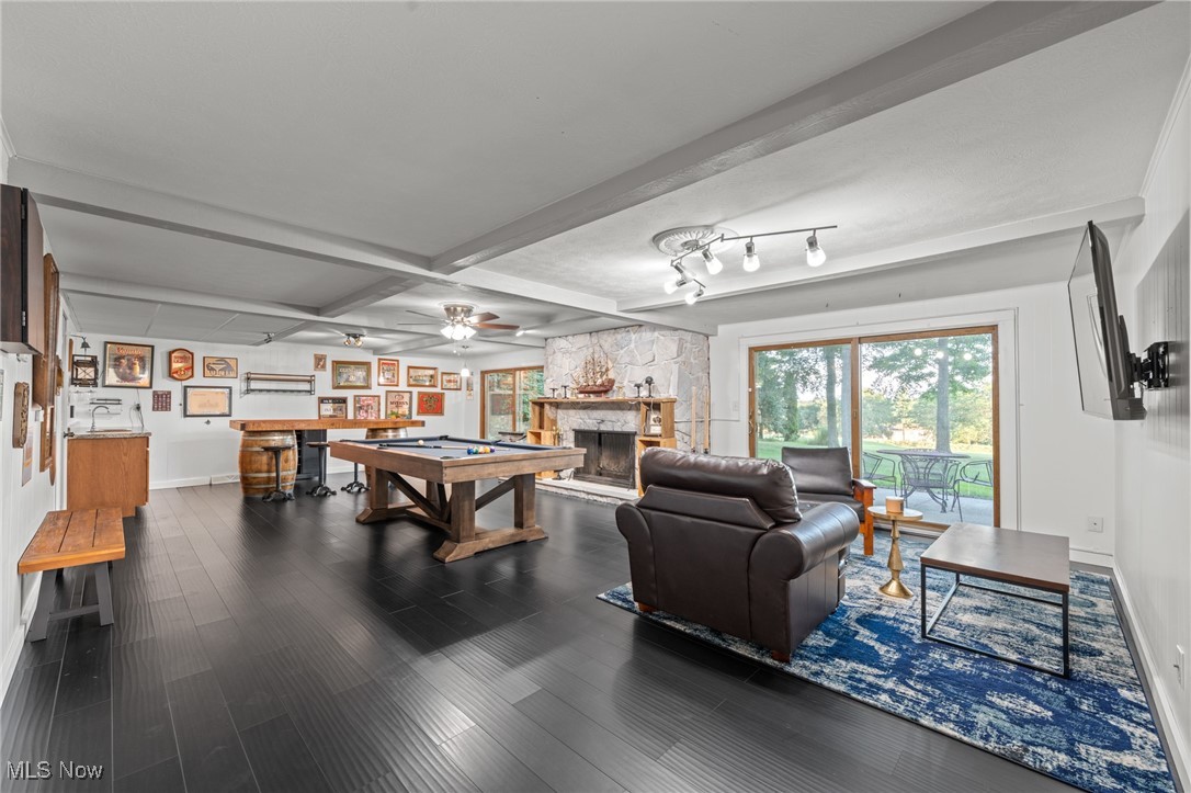 Game room with a pool table, stone fireplace, leather seating, and sliding doors to a patio.