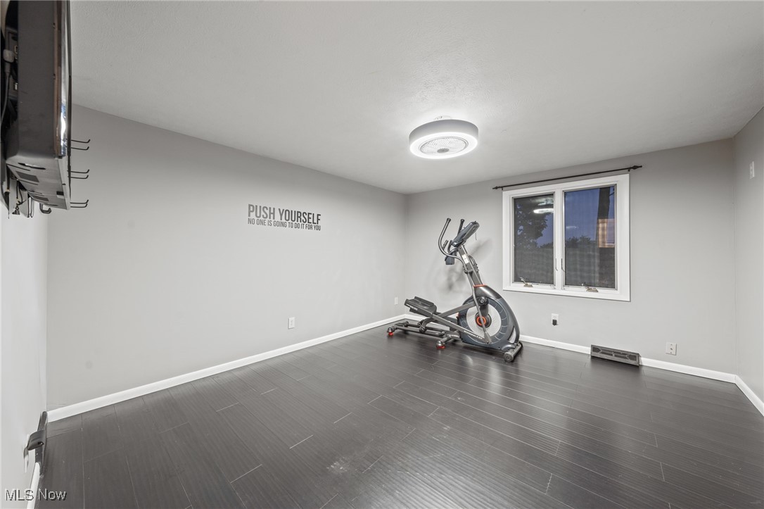 Home gym with an elliptical machine, dark tile flooring, and a motivational wall quote.