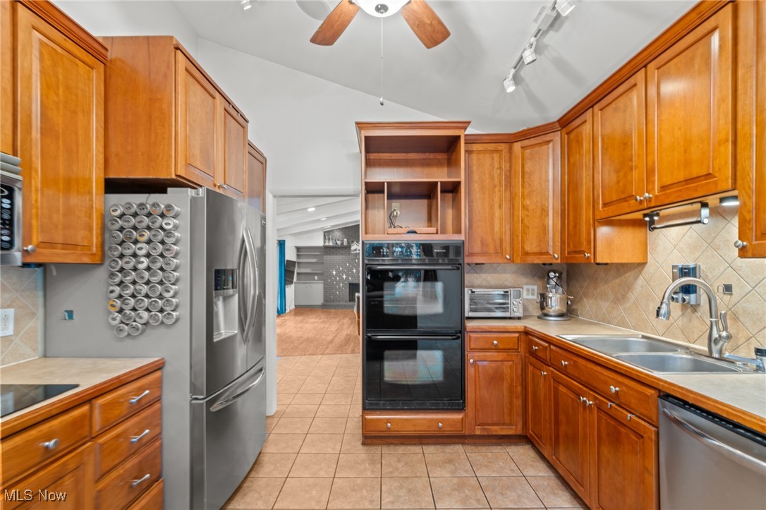 Kitchen with warm wood cabinets, stainless appliances, double wall oven, and tiled floors.