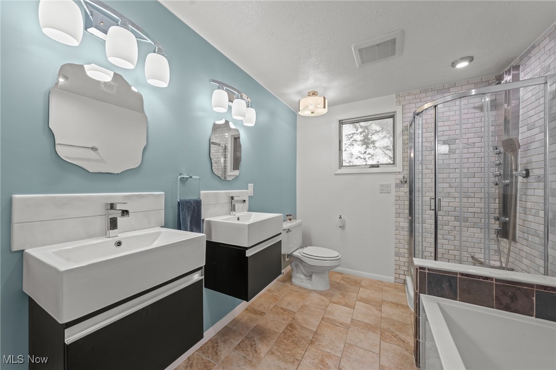 Bathroom with double vessel sinks, blue walls, a glass shower, and a bathtub.