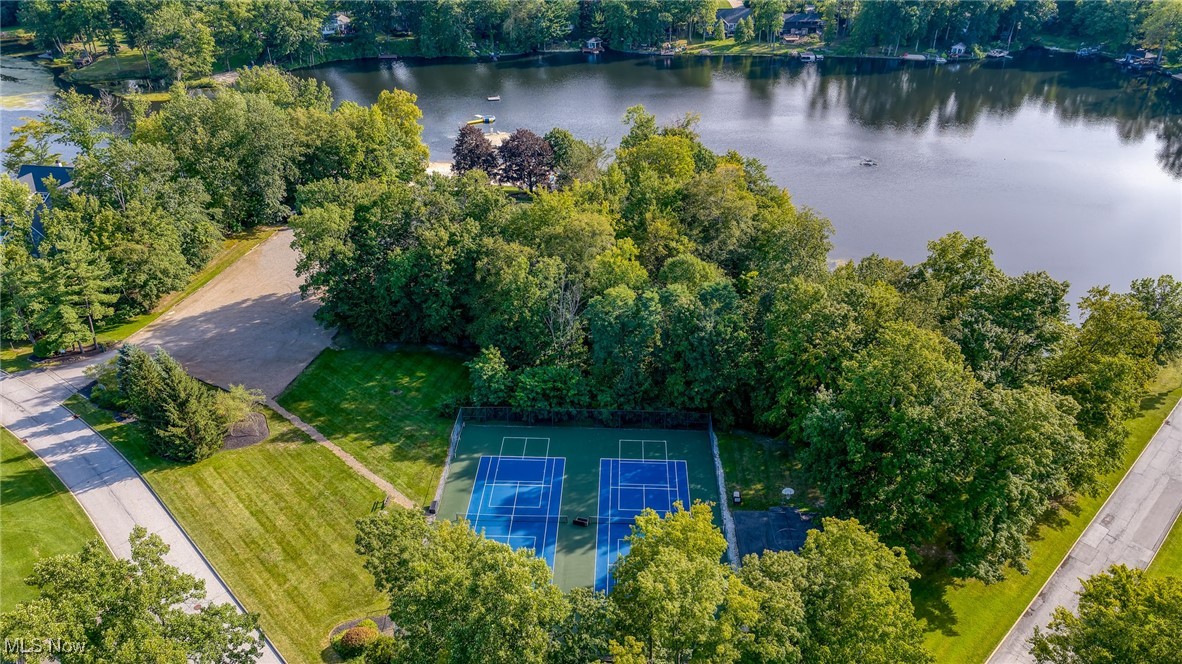 Aerial view of lakeside grounds with two tennis courts, lawns, and mature trees.