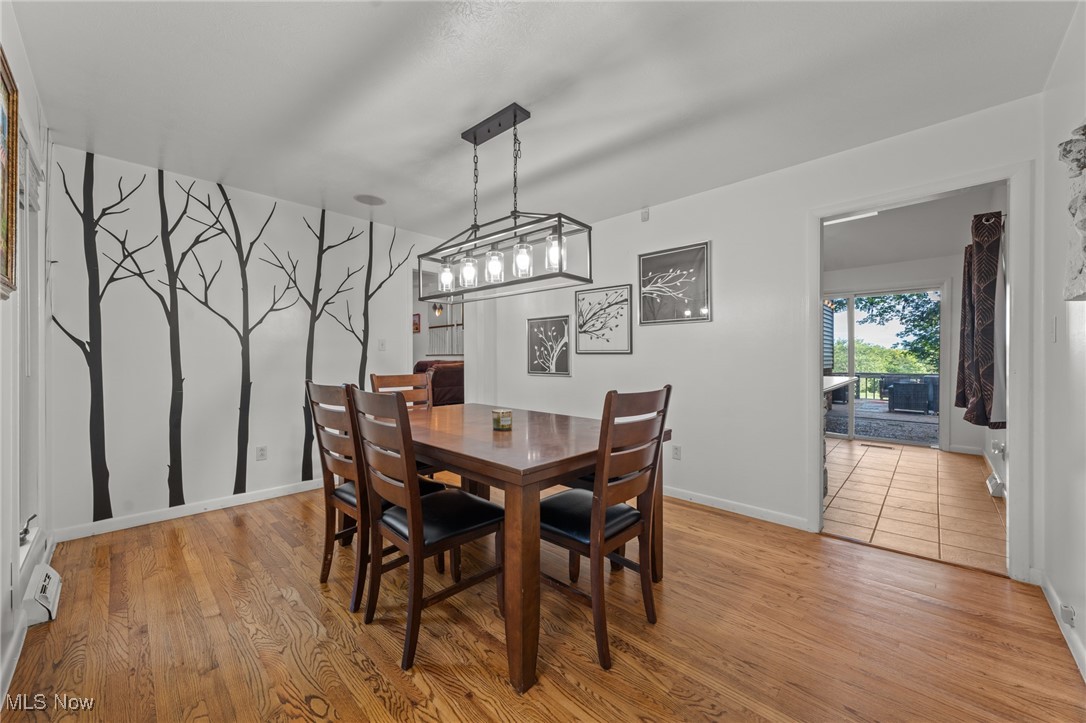 Dining room with a tree mural, wooden table and chairs, and a doorway to a sunroom.